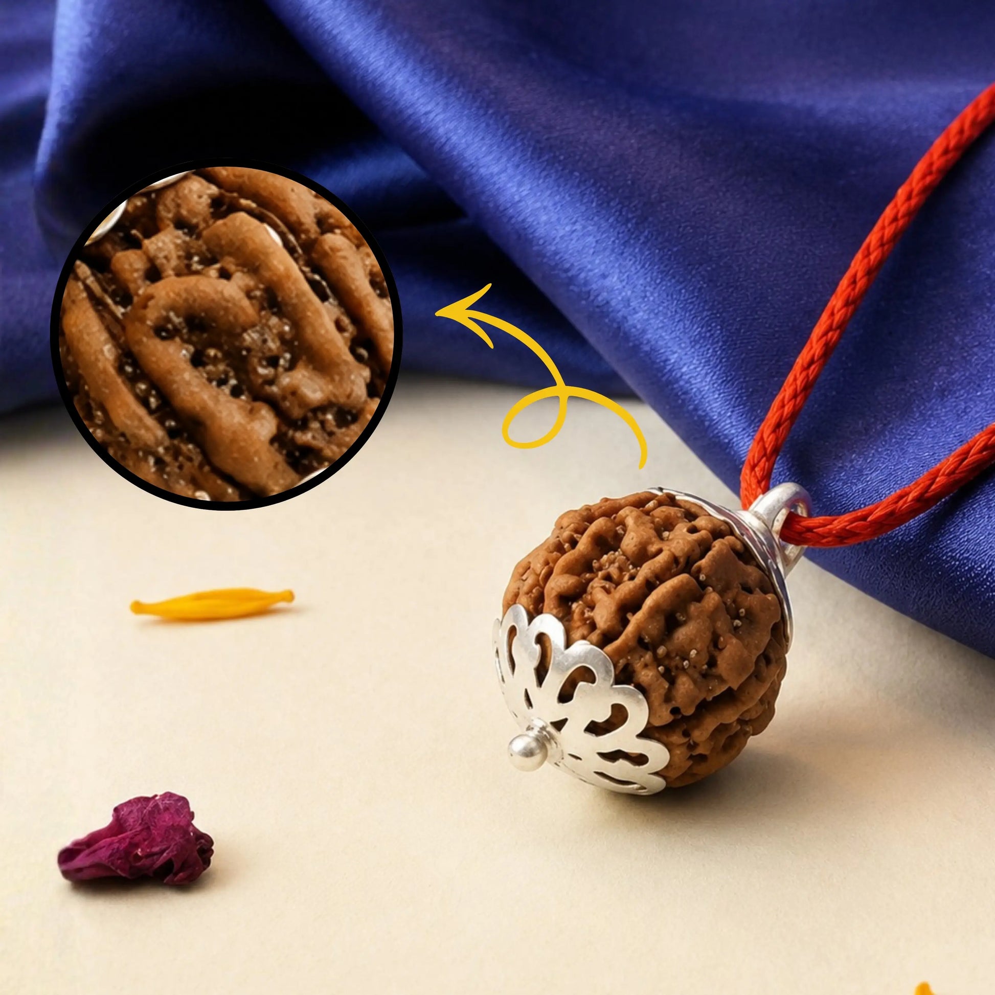 Brown pendant with intricate design on a red cord against a blue fabric background