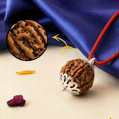 Brown pendant with intricate design on a red cord against a blue fabric background